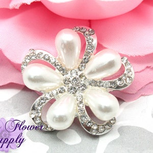 May include: A silver flower-shaped embellishment with five white pearl-like accents and a center of clear rhinestones.
