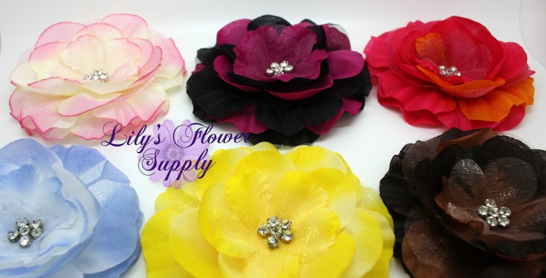 May include: Six fabric flower hair clips in various colors, including pink, red, yellow, blue, brown, and purple. Each flower has a rhinestone center.