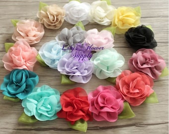 May include: Assortment of 14 handmade fabric flower hair clips in various colors, including pink, blue, red, yellow, and white. Each flower has a layered, ruffled design and is attached to a green leaf.