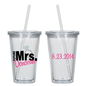 May include: Two clear plastic tumblers with straws. One tumbler has the text "Future Mrs. Donovan" with a diamond ring graphic. The other tumbler has the date "8.23.2014".