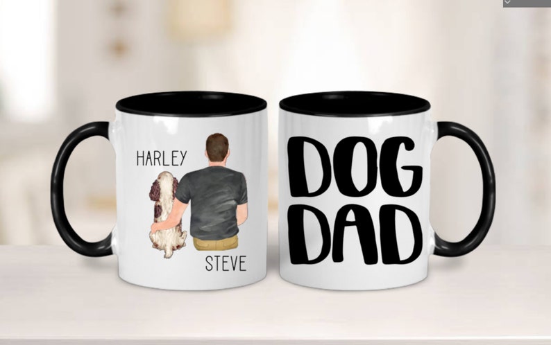 May include: Two white ceramic mugs with black rims. One mug features a cartoon illustration of a person with a dog, with the text "Harley" and "Steve". The other mug has the text "DOG DAD" in black.