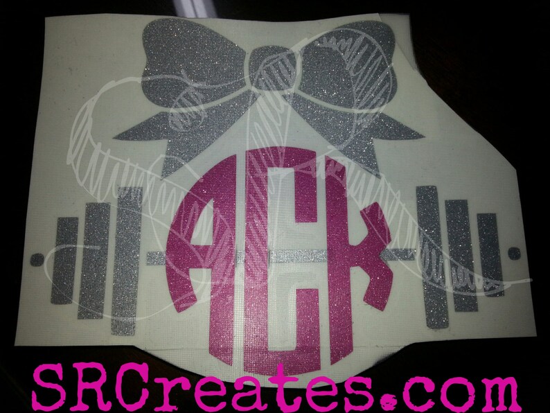 Op de afbeelding: Een zilveren glitter halterstang met een roze glitter monogram "ACK" en een zilveren glitter strik erbovenop. Het ontwerp is op een witte achtergrond.