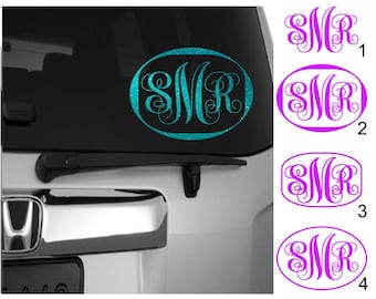 May include: Four variations of a monogram decal with the letters "SMR" in a cursive font. The first decal is turquoise blue with a glitter finish. The remaining three decals are purple. The decals are shown on a white car.