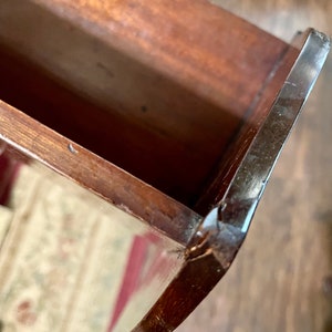 May include: Close-up of the inside of a wooden drawer with a dark brown finish. The drawer has a slight crack on the edge.