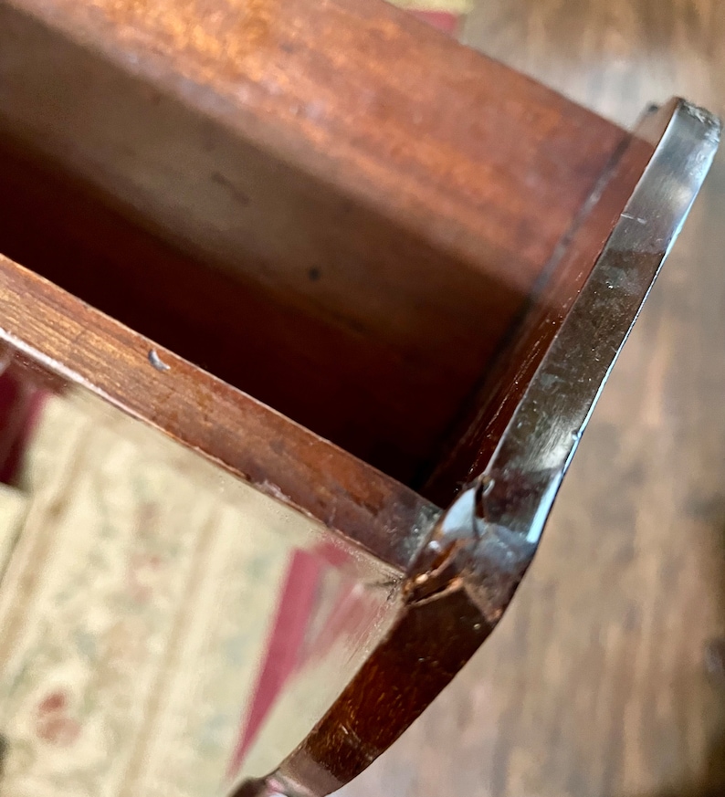 May include: Close-up of the inside of a wooden drawer with a dark brown finish. The drawer has a slight crack on the edge.