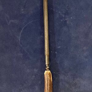 May include: A long, thin, metal knife sharpener with a brown antler handle.