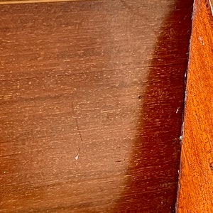 May include: Close-up of a wooden surface with a light brown finish. The surface has a smooth, polished look with a subtle grain pattern. The wood appears to be part of a box or cabinet.