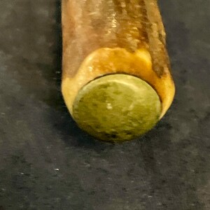 May include: Close-up of a wooden walking stick with a brown and green antler handle.