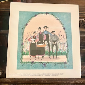 May include: A vintage print of a painting depicting a family of four Amish people standing in a field of purple flowers. The family is wearing traditional clothing and the man is holding a basket. The print is titled "The Generations" and is signed by the artist, "P. Buckley Moss".