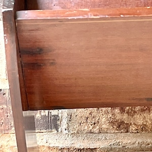 May include: A wooden crib with a dark brown finish. The crib has a simple design with a rectangular shape and a flat top. The crib is made of solid wood and has a sturdy construction.