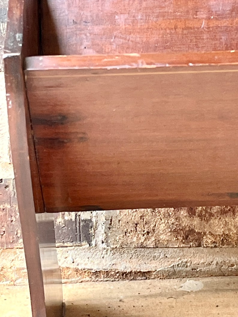 May include: A wooden crib with a dark brown finish. The crib has a simple design with a rectangular shape and a flat top. The crib is made of solid wood and has a sturdy construction.