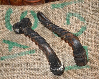 May include: Two antique black metal door handles with a twisted design. The handles have a heart-shaped design at the top and a round knob at the bottom.