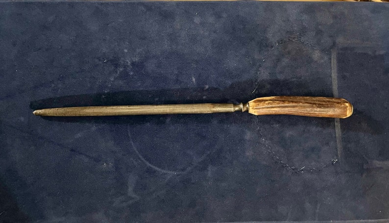 May include: A metal knife sharpener with a brown antler handle.