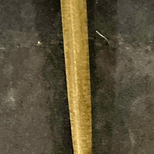 May include: A close-up of a gold-colored metal rod with a smooth, slightly textured surface.
