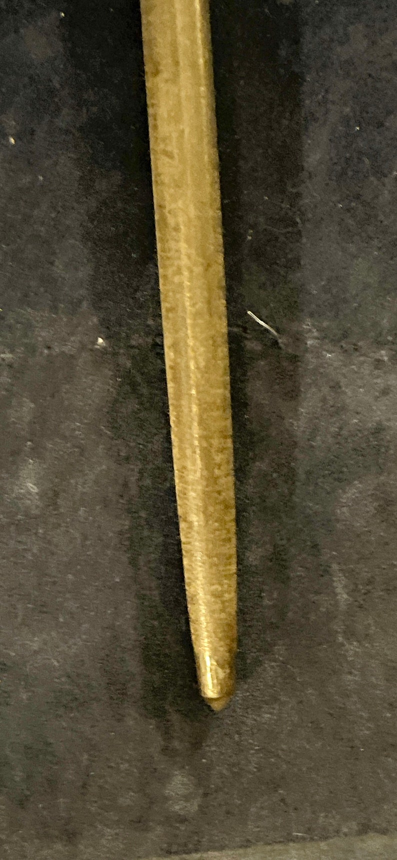 May include: A close-up of a gold-colored metal rod with a smooth, slightly textured surface.