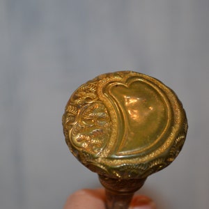 May include: A gold-colored walking stick handle with an ornate design featuring a heart shape.