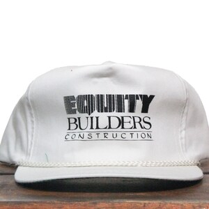 Puede incluir: Gorra de béisbol blanca con un logotipo negro que dice "EQUITY BUILDERS CONSTRUCTION"