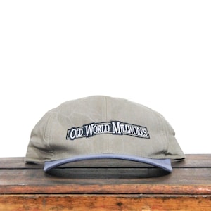 May include: A green and gray baseball cap with the text "Old World Millworks" embroidered in black on the front.