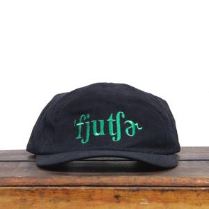May include: Black baseball cap with green embroidered text that reads "fjutfør"
