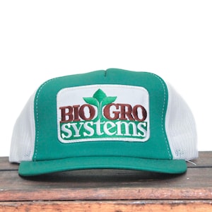 May include: A green and white trucker hat with the text "BIO GRO SYSTEMS" in brown and white. The hat features a green brim and a white mesh back. The logo includes a green leaf design.