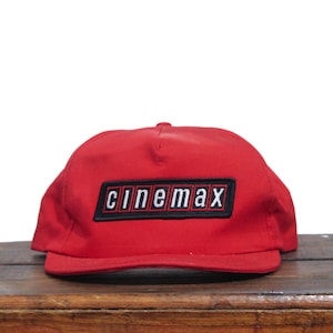 May include: Red baseball cap with a black and white embroidered patch that says "Cinemax".