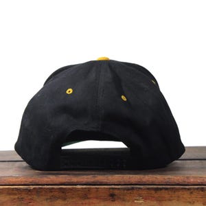 May include: A white ceramic mug with a black handle and the text "But First, Coffee" in a black, handwritten-style font. The mug is on a white surface.