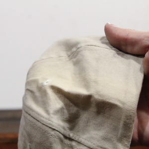 May include: A beige baseball cap with a slight crease on the top. The cap is made of a soft, textured fabric.