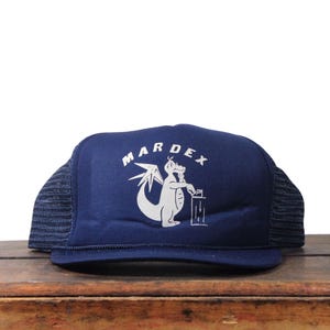 Può includere: Cappellino da camionista blu navy con grafica bianca di un drago e la scritta "MARDEX". Il cappello ha un retro in rete e una visiera curva. Un accessorio casual per l'uso quotidiano.