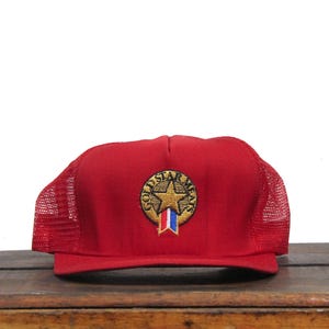 Könnte beinhalten: Rote Mesh-Trucker-Kappe mit einem goldenen Stern und den Worten "Gold Star Meals", die auf der Vorderseite gestickt sind.