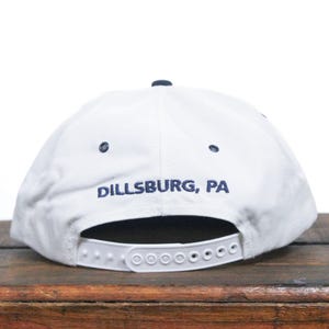 K&ouml;nnte beinhalten: Wei&szlig;e Baseballkappe mit einem marineblauen Schirm und einem marineblauen gestickten Logo mit der Aufschrift "Dillsburg, PA".