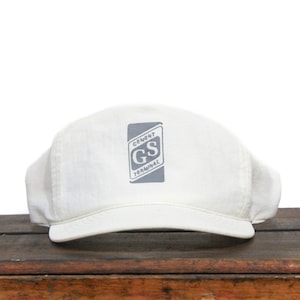 May include: A white baseball cap with a gray patch on the front that says "Cement GS Terminal".