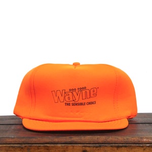 May include: Orange and black baseball cap with the text "DOG FOOD Wayne THE SENSIBLE CHOICE" on the front.