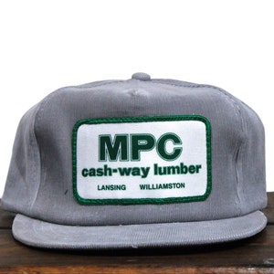 May include: Gray corduroy trucker hat with a green and white patch that reads "MPC cash-way lumber LANSING WILLIAMSTON"
