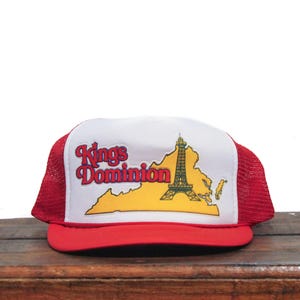 May include: Red and white mesh trucker hat with a yellow and white patch featuring the text "Kings Dominion" and a graphic of a tower.