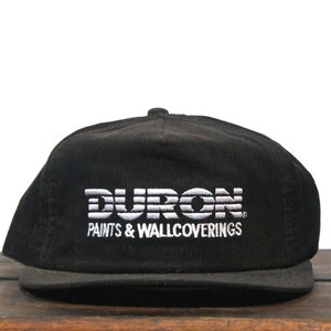 May include: Black corduroy baseball cap with a white embroidered logo that reads "DURON PAINTS & WALLCOVERINGS".