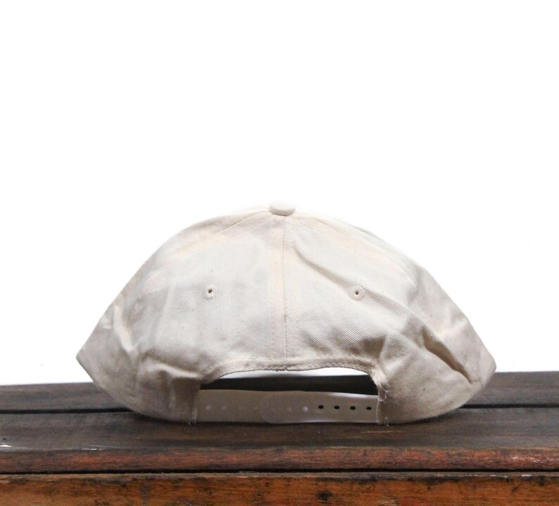 May include: A white baseball cap with a slightly distressed look. The cap has a flat brim and a white adjustable strap.