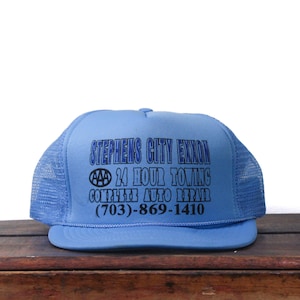 Könnte beinhalten: Hellblaue Trucker-Cap mit Mesh-Rückseite und gebogenem Schirm. Auf der Vorderseite steht in schwarzer Schrift "Stephens City Exxon", "24 Hour Towing" und "Complete Auto Repair" sowie eine Telefonnummer.