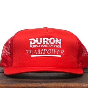 May include: Red and white trucker hat with the text "DURON PAINTS & WALLCOVERINGS TEAMPOWER" on the front.