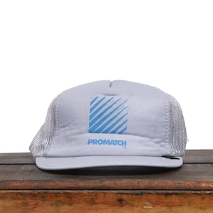 May include: A grey and white trucker hat with a blue and white striped logo that says "PROMATCH TM".