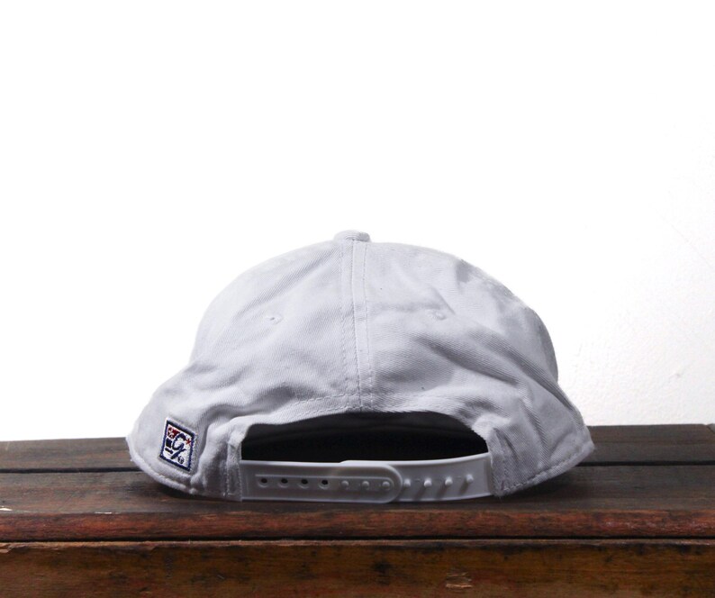 Pu&ograve; includere: Un cappellino da baseball grigio chiaro con visiera piatta e chiusura a scatto regolabile. Il cappellino presenta una piccola toppa ricamata sul lato. Il cappello &egrave; realizzato in un tessuto morbido e resistente.