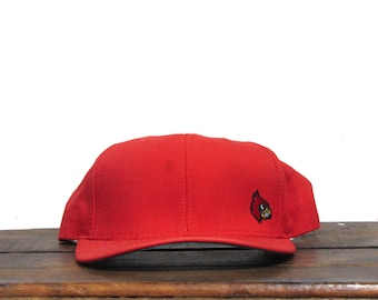 May include: A red baseball cap with a black embroidered cardinal logo on the front.