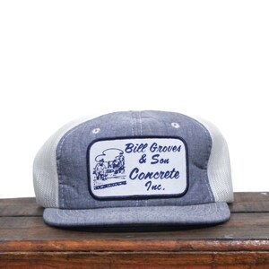 May include: A blue and white trucker hat with a patch that reads "Bill Groves & Son Concrete Inc.".