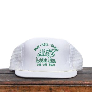 May include: White mesh trucker hat with a green logo that reads "BUY - SELL - TRADE AEZ Loan Inc. 304-263-8000"