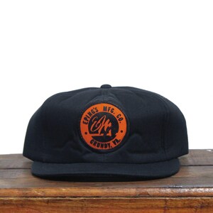 Puede incluir: Gorra de béisbol negra con un parche redondo naranja que dice "Eping's Mfg. Co. Grundy, Va."