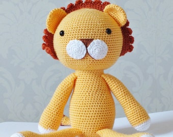 Può includere: Un leone di peluche lavorato a uncinetto con corpo giallo, criniera marrone e tratti del viso bianchi.