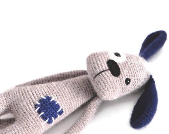 May include: A gray crocheted stuffed dog with blue ears and a black nose. The dog has a blue patch on its body.