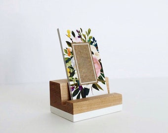 May include: A white wooden picture frame with a floral design and a brown paper insert. The frame is sitting on a white wooden stand.