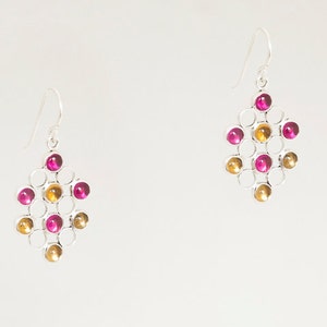 May include: Silver earrings with a geometric design featuring pink and gold round stones.