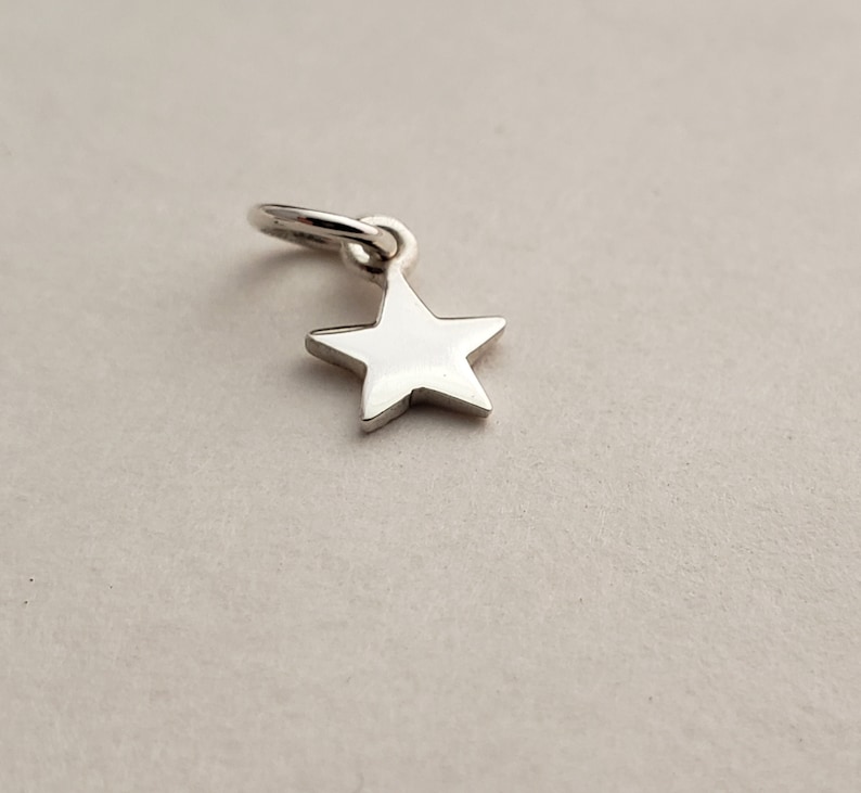 May include: A silver star charm with a loop for attaching to a necklace or bracelet.
