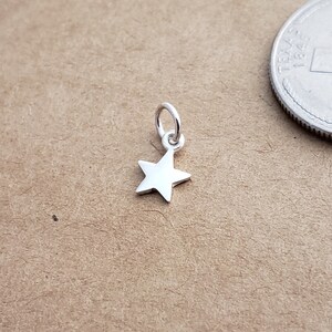 May include: A small silver star charm with a loop for attaching to a necklace or bracelet.
